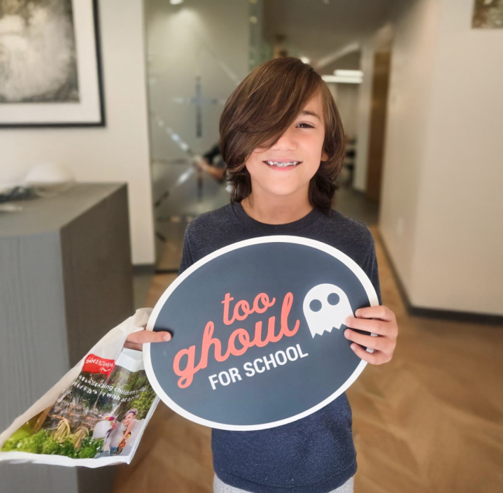 A happy patient holding a sign saying, "too ghoul for school."