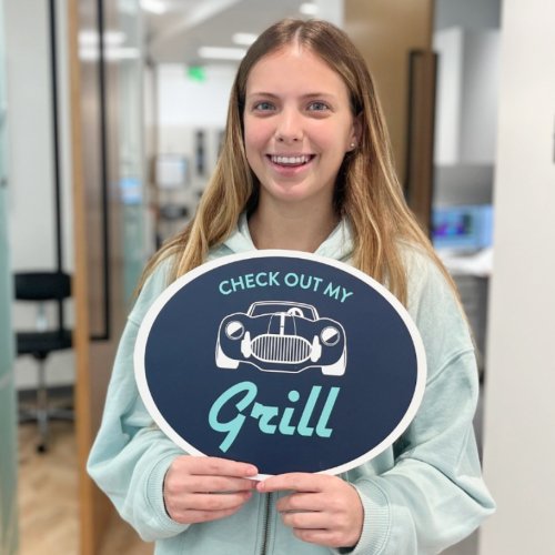 A patient posing for a picture with a sign that says, "check out my grill."