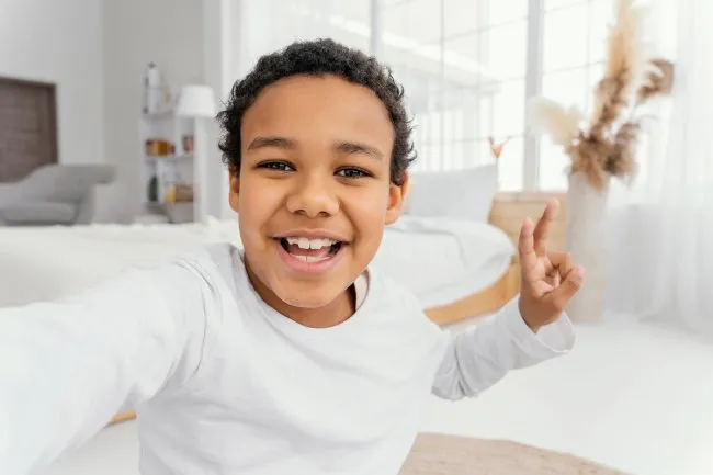 A smiling boy holding up a peace sign.